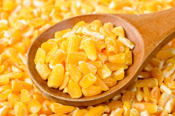 yellow corn grits in the wooden spoon, tilt shift lens