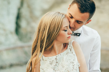 bride and groom posing on the mountain on a sunny day