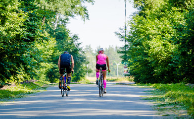 Obraz premium Young pair of professional cyclists riding on the road 