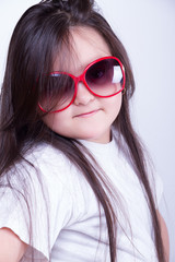 Fototapeta premium Portrait of a young girl in sunglasses on a gray background