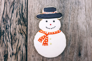 Snowman cookie on grunge wooden board.