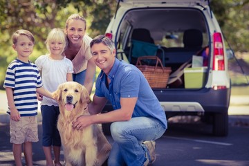 Happy family smiling at the camera with their dog