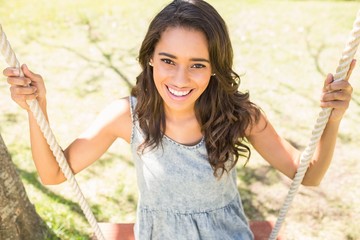 Pretty brunette swinging in park 