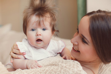 Portrait of happy mother with baby,posing lying on the bed