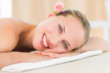 Obraz na płótnie Canvas Peaceful blonde lying on towel smiling at camera