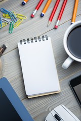 Notepad next to the cup tablet smartphone and mouse 