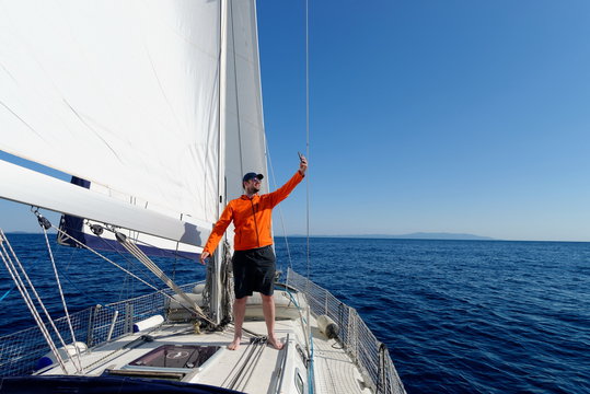 Man sailing with sails out on a sunny day and making selfie