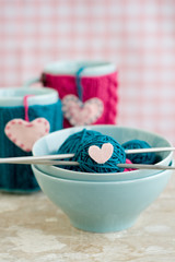 Bright balls of yarn in blue plates and handmade from felt heart