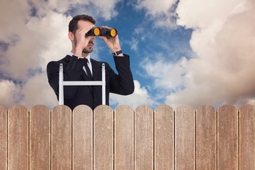 Composite image of businessman looking on a ladder