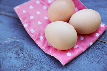 Eggs on tablecloth over wooden background