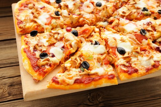 Al funghi pizza with olives cut in sectors on wooden board