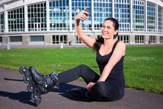 happy woman in roller skates sitting and making selfie photo on