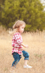 Naklejka na ściany i meble Stylish kid girl 2-3 year old walking in meadow. Childhood. Country side. 