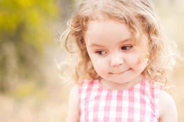 Close up portrait of cute baby girl 2-3 year old posing outdoors. Cute child. Looking away. Childhood.