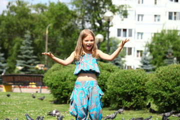 Fototapeta premium Happy little girl feeding doves in the city street