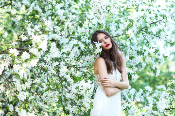 Portrait of young beautiful woman in spring blossom trees.