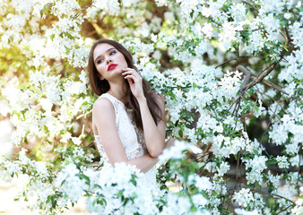 Portrait of young beautiful woman in spring blossom trees.