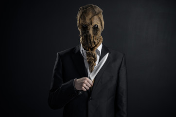 Fear and Halloween theme: a brutal killer in a mask holding a knife on a dark background in the...
