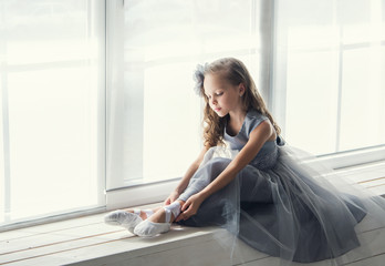 A little adorable young ballerina sitting on window © jutaphoto