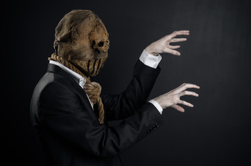 Fear and Halloween theme: a brutal killer in a mask on a dark background in the studio