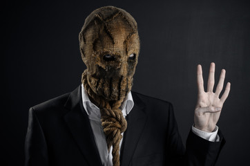 Fear and Halloween theme: a brutal killer in a mask on a dark background in the studio