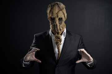 Fear and Halloween theme: a brutal killer in a mask on a dark background in the studio