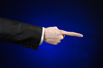 Businessman and gesture topic: a man in a black suit and white shirt showing hand gesture on an isolated dark blue background in studio