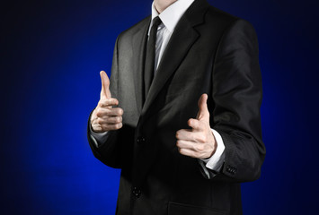 Businessman and gesture topic: a man in a black suit and white shirt showing gestures with hands on a dark blue background in studio isolated