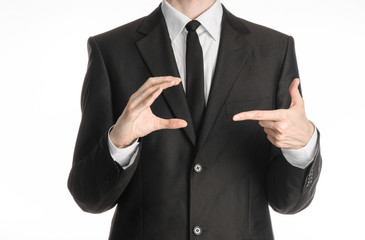Businessman and gesture topic: a man in a black suit and tie holds his right hand and pointing to her left isolated on white background in studio