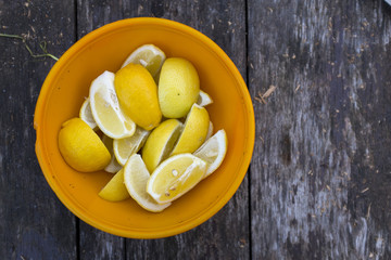 Quarters of lemons in yellow plate on wooden table