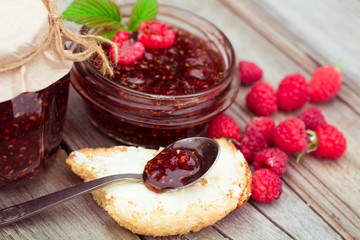 Raspberry jam and fresh raspberry on a rustic wooden table. DOF