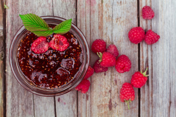 Raspberry jam and fresh raspberry on a rustic wooden table. DOF