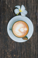 Coffee cup and flower figure on old wooden background