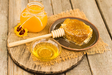 Honey in jar with honey dipper on wooden background