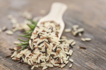 Verschiedene Reissorten in Holzschaufel auf rustikalem Holzbrett