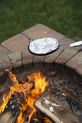 Cooking a pan of popcorn in a foil covered pan over a garden fire pit