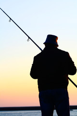Homem a pescar ao por-do-sol.
