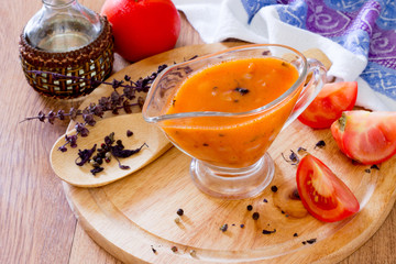 Tomato sauce in a glass gravy boat on a wooden table