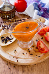 Tomato sauce in a glass gravy boat on a wooden table