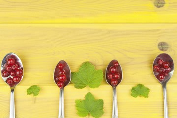 Coffee spoon with red currants on a yellow wooden table. Preparing for home baking currant...