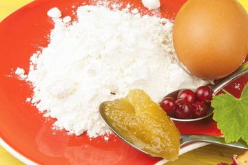 Ingredients for domestic production currant dessert. Flour, eggs, honey and red currants. Chef prepares the ingredients to bake a dessert.

