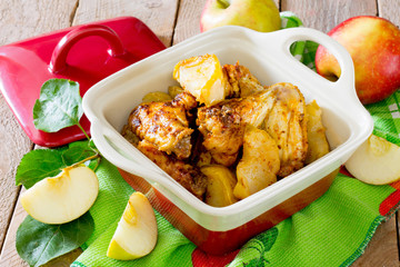 Baked chicken with apples on wooden table