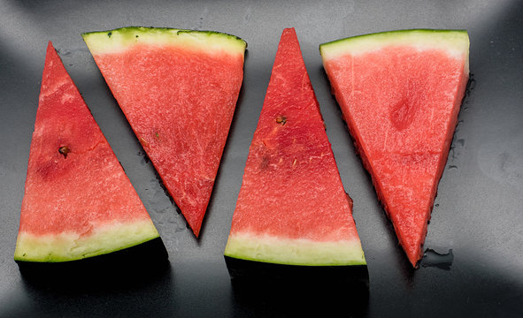 Four slices of watermelon against black background
