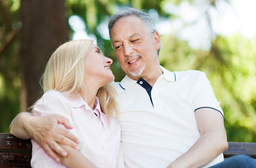 Obraz premium Happy mature couple sitting on a bench