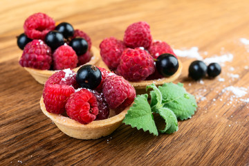 Sweet cakes with berries and mint on wooden  table close-up.
