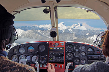 view from over snow covered peaks while flying in small plane