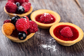 Sweet cakes with berries and jelly on wooden  table close-up.