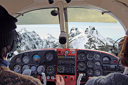view from over snow covered peaks while flying in small plane