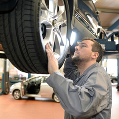 Gutachter in einer Werkstatt kontrolliert Auto für TÜV // car check in garage