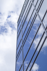 Fototapeta na wymiar New glass building with reflecting clouds